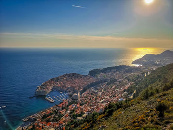 High angle view of townscape by sea against sky during sunset