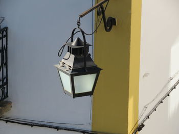 Low angle view of electric lamp hanging against wall