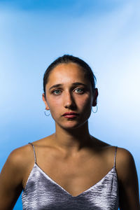 Portrait of young woman standing against blue background