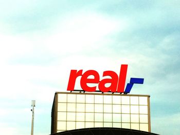 Low angle view of sign board against cloudy sky