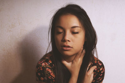 Close-up portrait of a young woman against wall