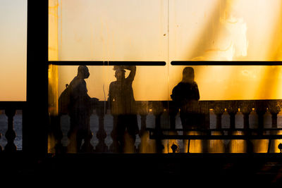 Silhouette people standing by glass window