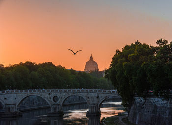 Bridge over river in city against clear sky