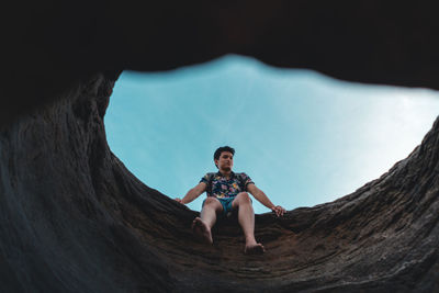 Portrait of smiling young man sitting against sky