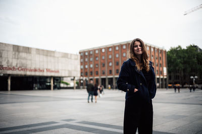 Portrait of woman standing against building