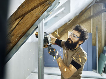 Construction worker cutting metal with grinder at site