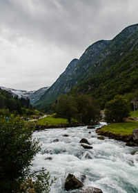 Scenic view of river by mountains against sky