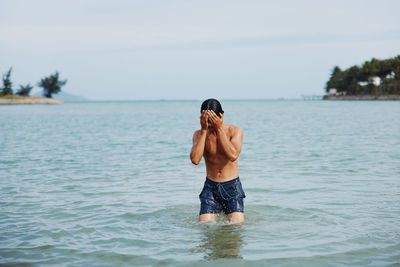 Rear view of woman swimming in sea against sky