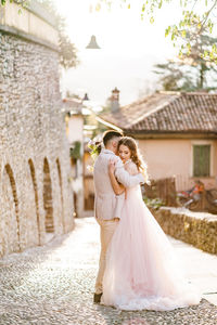 Couple holding umbrella while standing by wall