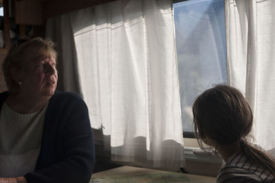 Side view of grandmother and daughter sitting by window in motor home