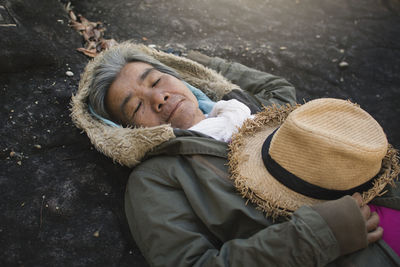 Portrait of smiling senior woman lying on rock at forest