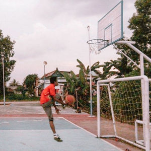 Rear view of man holding basketball hoop against sky