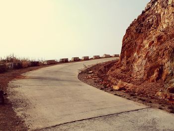 Road leading towards city against clear sky