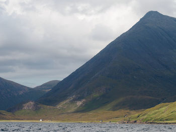 Scenic view of river by mountains against sky