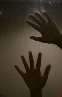 Cropped hands of wet window