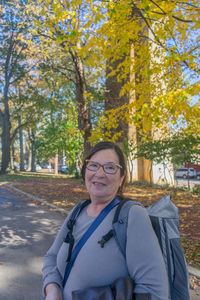 Portrait of young woman standing against trees