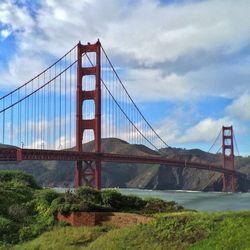 Suspension bridge against cloudy sky