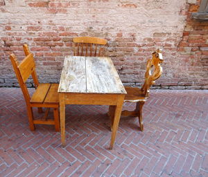 Table and chairs against brick wall