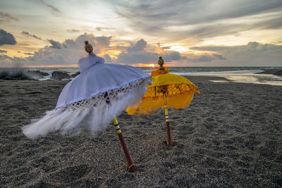 Umbrella on beach against sky during sunset
