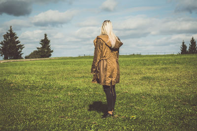 Rear view of woman walking on field against sky