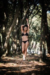 Portrait of young woman walking against trees in forest