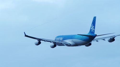 Low angle view of airplane flying against blue sky