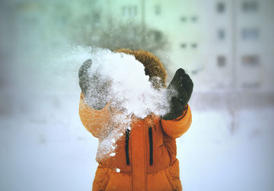 Close-up of man splashing water against sky