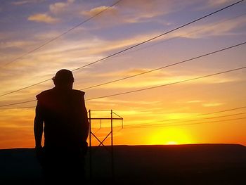 Rear view of silhouette man against sky during sunset