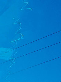 Low angle view of power lines against blue sky