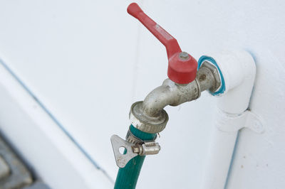 High angle view of garden hose in faucet against white wall