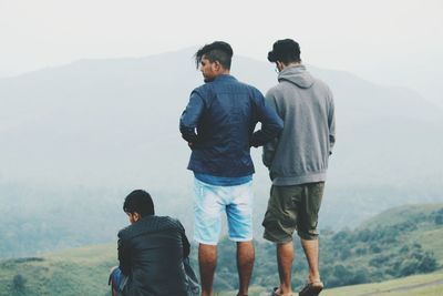 Rear view of friends walking on mountain against sky