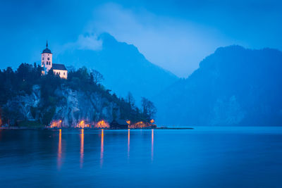 Scenic view of sea against buildings at dusk