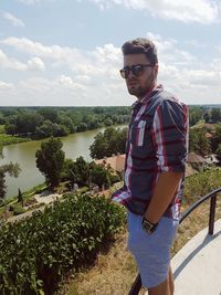 Portrait of young man standing against sky