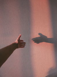 Cropped hand with shadow on wall