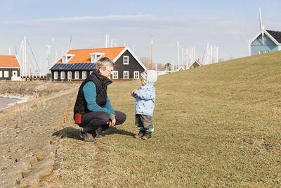 Full length of grandfather and granddaughter wearing warm clothing on field