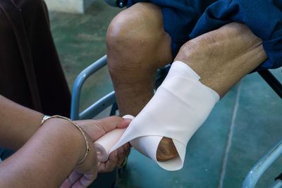 Cropped hand of doctor wrapping bandage on prosthesis leg in hospital