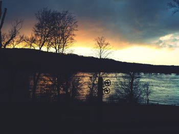 Silhouette trees by lake against sky during sunset