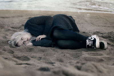 Rear view of woman lying on sand at beach