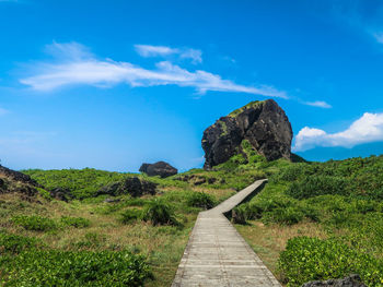 Footpath leading towards mountain against sky