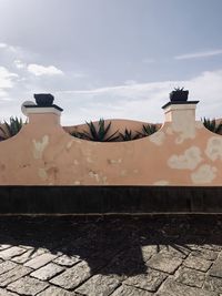 Birds on wall of building against sky