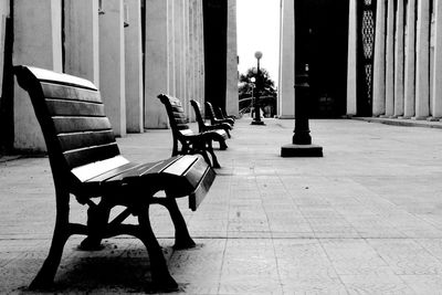 Empty chairs and table on floor against building