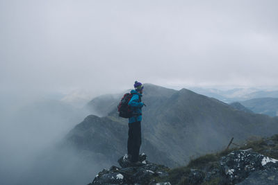 Man standing on mountain during foggy weather