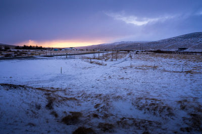 Scenic view of snowcapped field against sky during sunset
