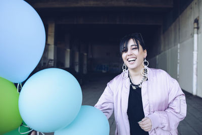 Cheerful young woman with balloons at parking lot