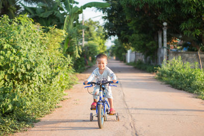 Smiling boy riding bicycle on road