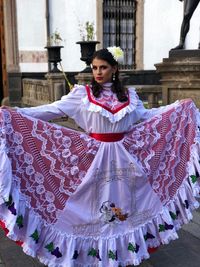 Portrait of young woman standing against wall