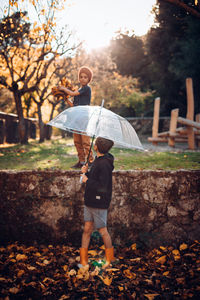 Full length of boy standing by tree during autumn