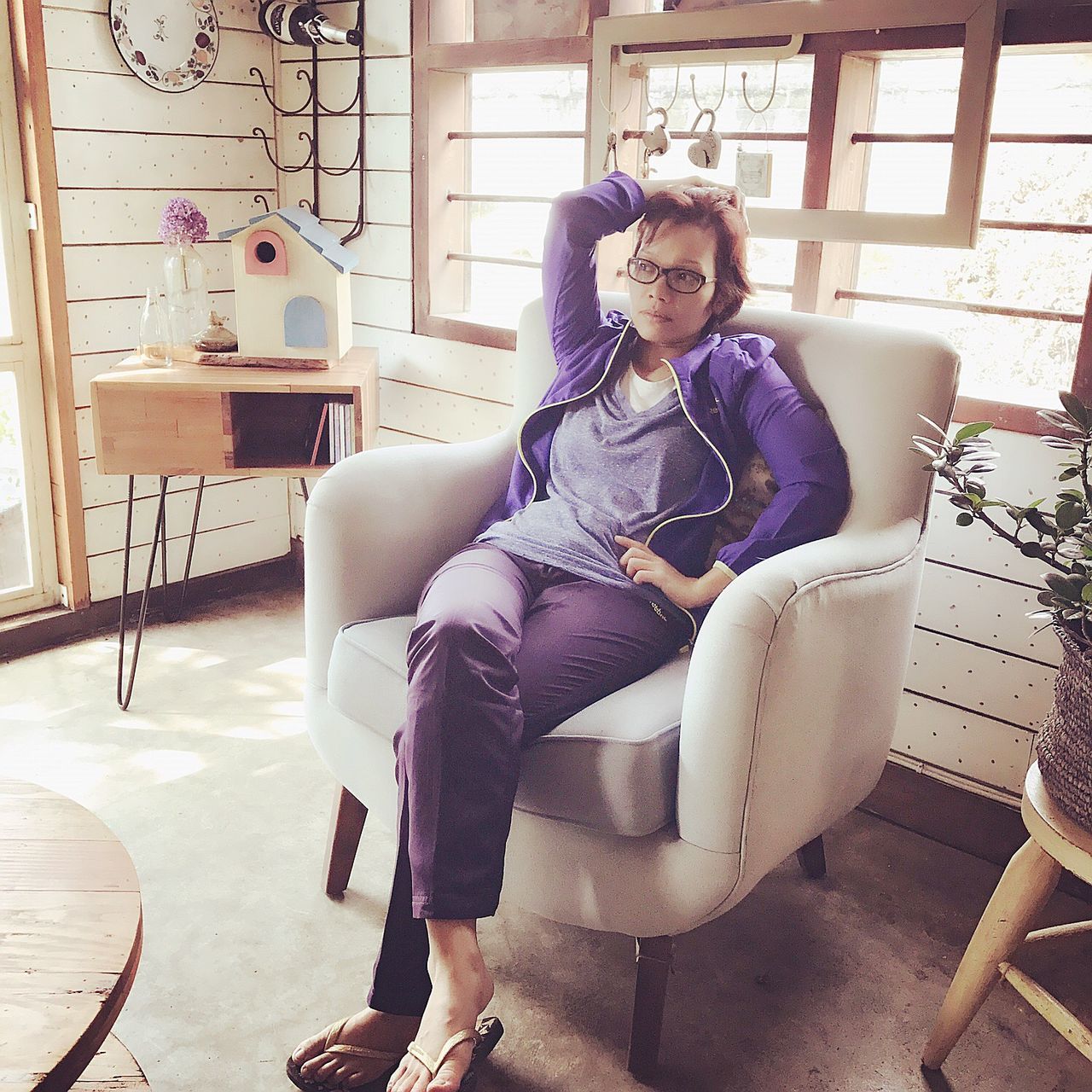 full length, sitting, one person, real people, indoors, casual clothing, home interior, front view, mature adult, mature women, looking at camera, young adult, eyeglasses, lifestyles, chair, portrait, young women, leisure activity, wireless technology, technology, beautiful woman, day, people