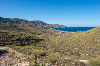 Scenic view of sea and mountains against clear blue sky