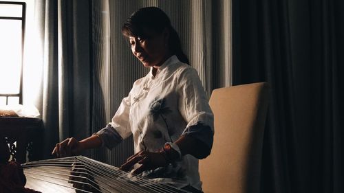 Woman playing string instrument at home